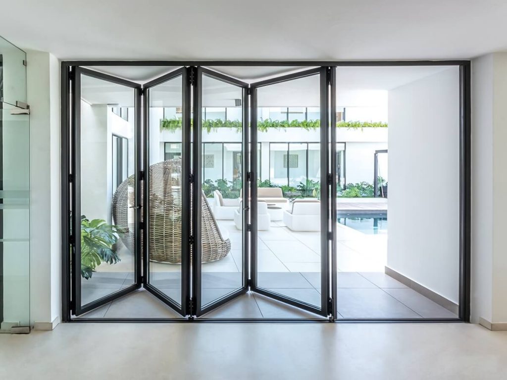 Cortizo aluminium bi-fold doors opening to a modern patio and pool, creating a seamless indoor-outdoor transition.