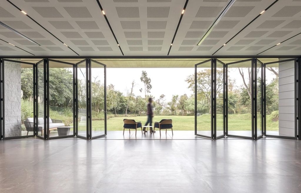 Cortizo aluminium bi-fold doors opening to a modern indoor-outdoor living space with a pool view.