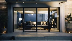 A modern living room with large glass sliding doors framed in sleek black, providing a seamless connection to the outdoor area. The image highlights the stylish and functional design of sliding doors, perfect for enhancing indoor-outdoor flow and adding a touch of elegance to any home.